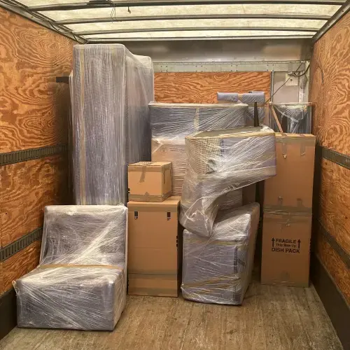 Loaded moving truck with wrapped furniture and labeled cardboard boxes