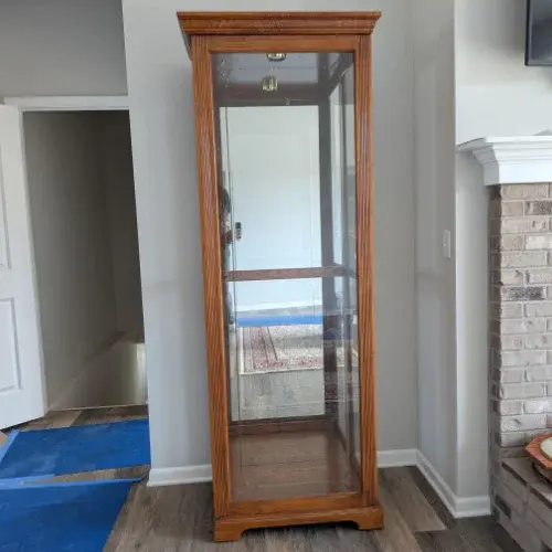 Tall glass display cabinet with wooden frame placed in living room corner