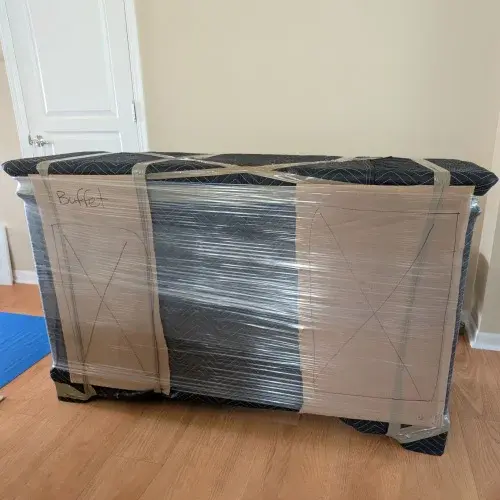 Buffet cabinet wrapped in moving blankets, cardboard, and stretch wrap