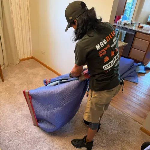 Mover folding a blue moving blanket inside a residential home