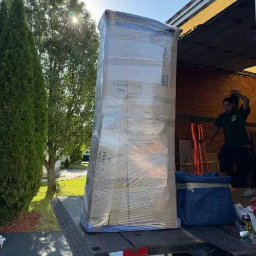 Tall furniture piece fully wrapped in blankets and stretch wrap on truck liftgate